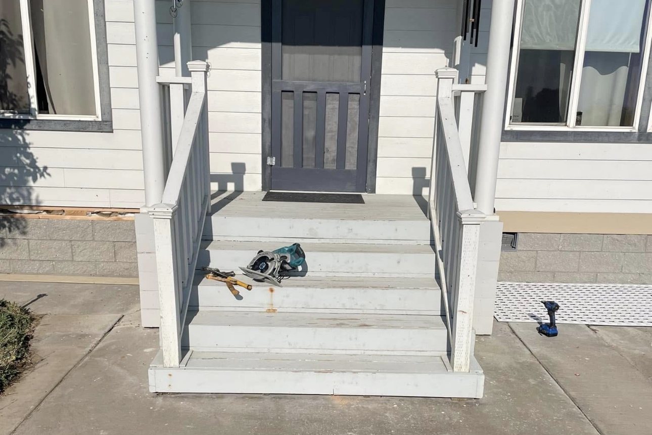 Front porch steps before the renovation, with worn painted treads and tools on the steps