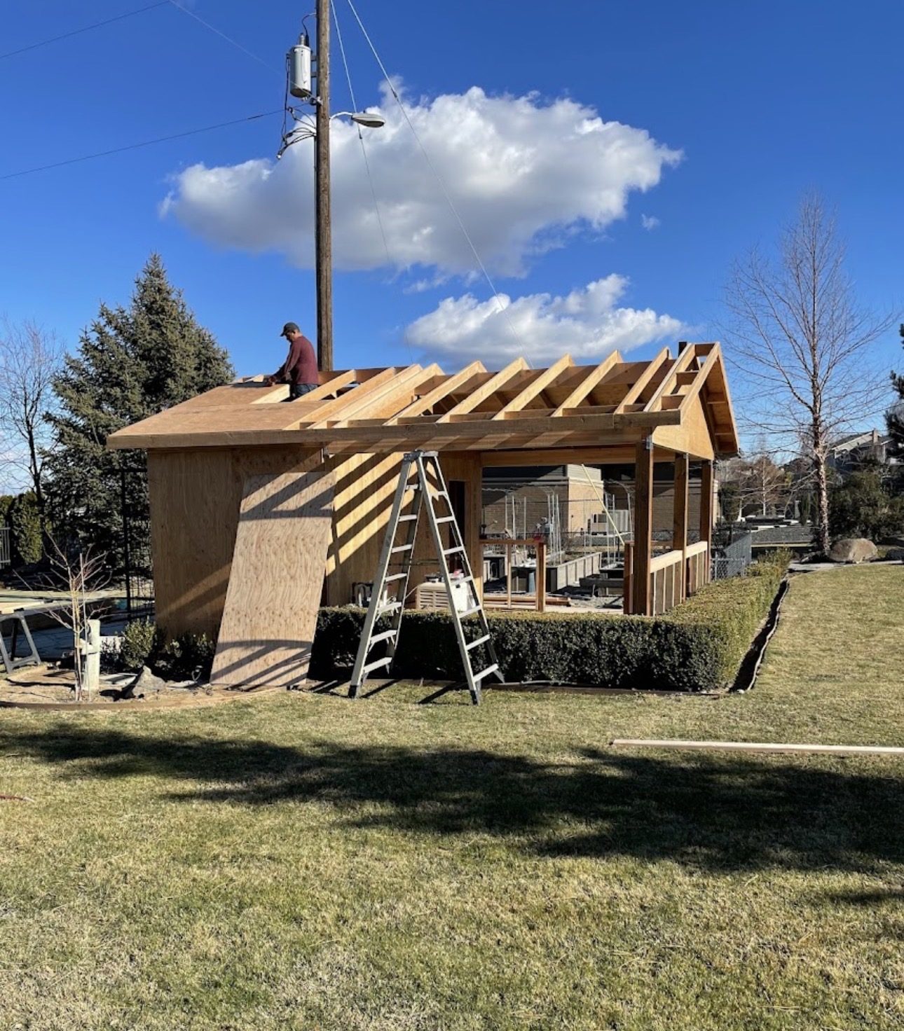 Crew member framing the roof of a custom pool house on a clear day